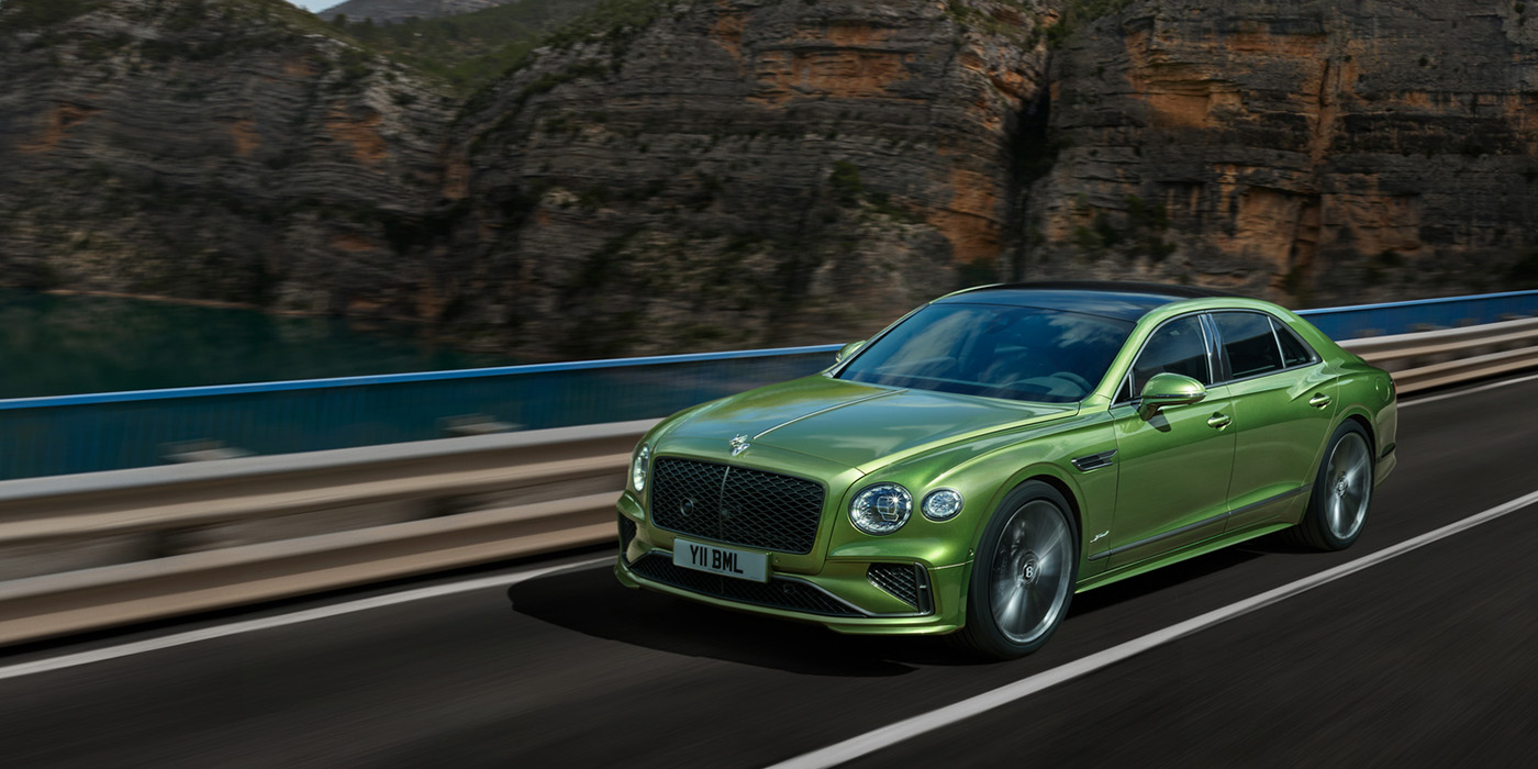 Bentley Lugano Bentley New Flying Spur Speed v8 hybrid sedan driving dynamically on a mountain road in Tourmaline Green paint
