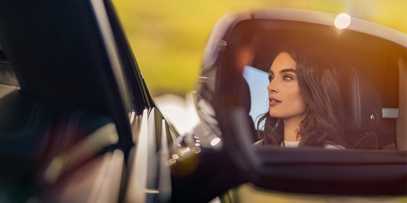 Bentley Lugano profile of dark haired woman's face in mirror of Bentley car in sunlight