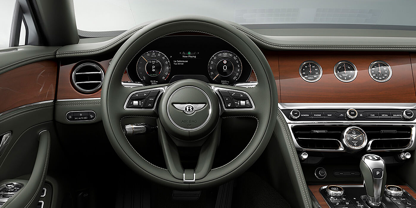 Bentley Lugano New Bentley Flying Spur sedan front cabin in Cumbrian Green hide and Crown Cut walnut veneer showing steering wheel and Rotating Display with three clocks on face