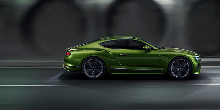  Bentley Lugano Bentley Continental GT coupe in Tourmaline Green paint driving in profile on a dark road