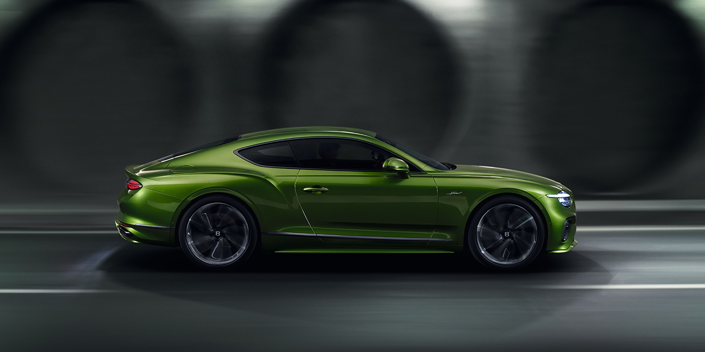Bentley Lugano Bentley Continental GT coupe in Tourmaline Green paint driving in profile on a dark road